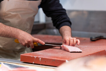 A fishmonger skillfully fillets a fresh fish with a large knife at a seafood market. The scene captures the essence of fresh, healthy, and protein-rich seafood