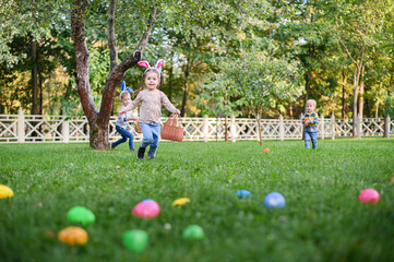 Children Hunting Easter Eggs in the Garden with Bunny Ears