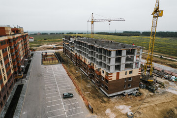 Construction site background. Hoisting cranes and new multi-storey buildings. Industrial background. Building construction site work against blue sky monolithic technology.