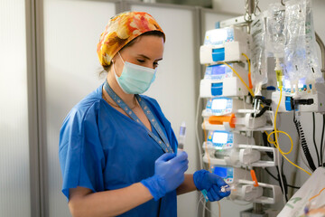 Nurse preparing syringe next to medical infusion pump in hospital room
