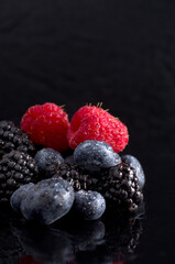 Fresh Berries, Raspberries,Blueberries and Blackberries on Black Wet Surface