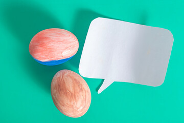 Colorful eggs and speech bubble on turquoise background, top view
