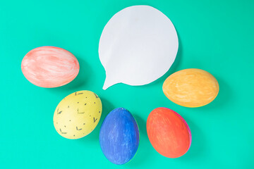 Colorful painted Easter eggs with a speech bubble on a green background.