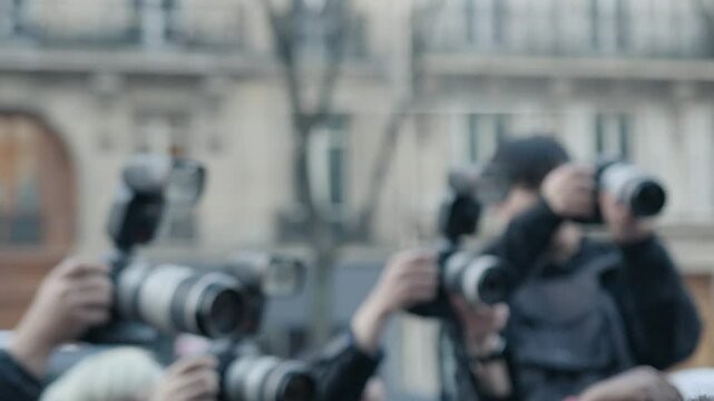 Paparazzi taking photos of celebrity arriving in car