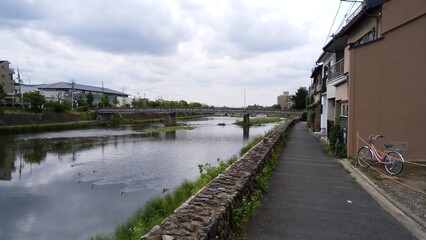 "Kyoto" is written in Japanese. Kyoto Prefecture, Japan, has many temples and shrines. It is a landscape with a lot of nature.