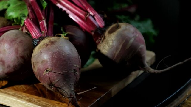 Freshly harvested beetroots rest on a wooden surface, their deep purple skins rich with earthy texture.