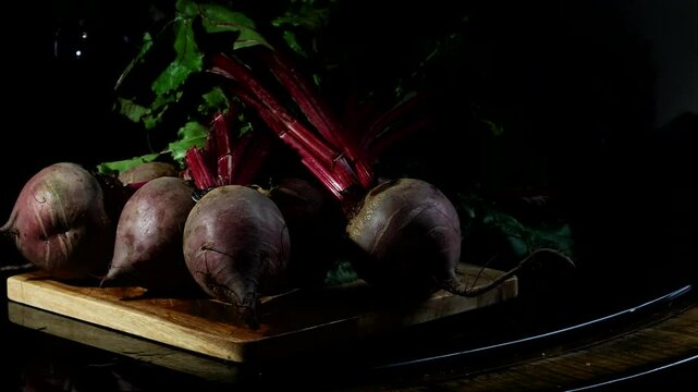 Freshly harvested beetroots rest on a wooden surface, their deep purple skins rich with earthy texture.