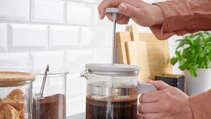 Closeup of a person preparing coffee in a french press coffee maker.
