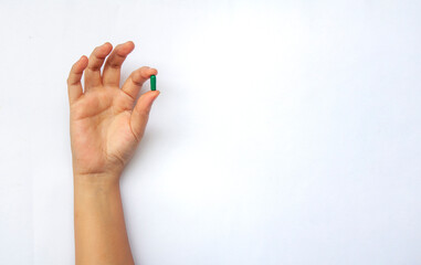 Hand holding green pill or capsule with customizable space for text. Medical and health matters...