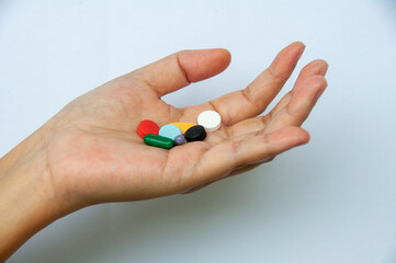 Hand showing variety of colorful pills and capsules with customizable space for text. Medical and health matters concept.