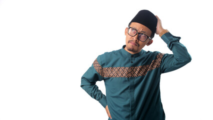 Asian Muslim man appears doubtful as he scratches his head while deep in thought, trying to find a...