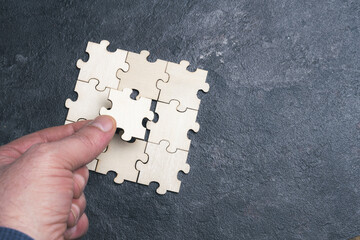A person holds a puzzle piece and is about to place it. This represents solving a problem or...