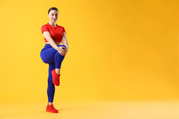 Woman in sportswear exercising on orange background, space for text