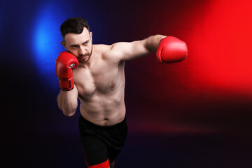 Man with boxing gloves fighting on dark background in neon lights