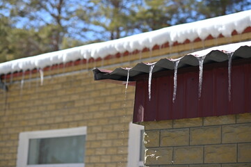 Spring drip from the roof of the house. A row of icicles. Melting snow.