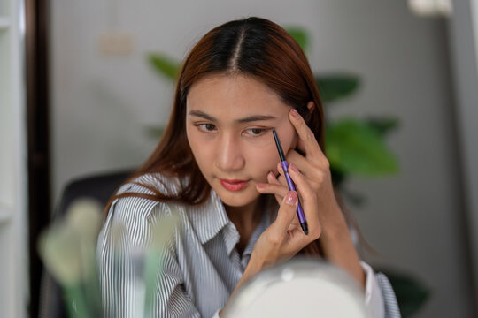 Eye Makeup and Precision. A woman skillfully applying eyeliner for a polished look.