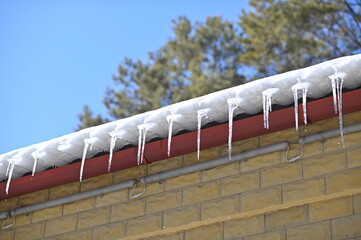 Spring drip from the roof of the house. A row of icicles. Melting snow.