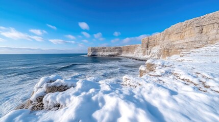 Snowy coastal cliffs meet icy ocean