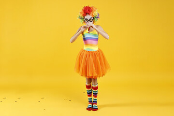 Girl dressed like clown with blowers on yellow background. Surprise party