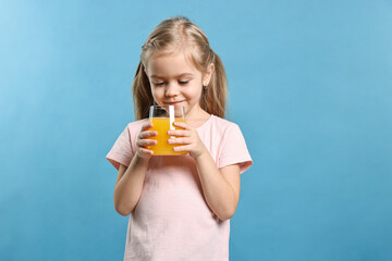Girl with glass of orange juice on light blue background. Refreshing drink