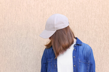 Woman in stylish baseball cap near beige wall. Mockup for design