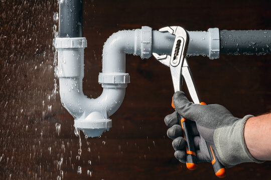Plumber fixing a water leak in a sink drain. Emergency plumbing breakdowns repair.