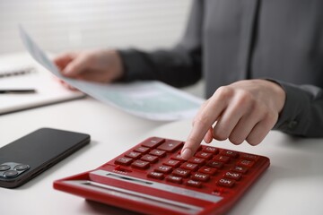 Budget. Woman with paperwork and calculator at white desk indoors, closeup
