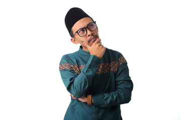 Obraz premium Confused Asian Muslim man, with a pensive hand on his chin, looking up thoughtfully, isolated on a white background
