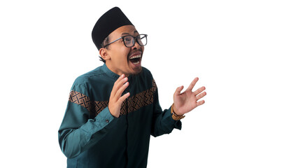Shocked and surprised Asian Muslim man stands with his mouth open and hands spread wide, expressing excitement. Isolated on a white background