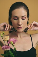 Fototapeta premium Woman with flowers posing gracefully against a yellow background