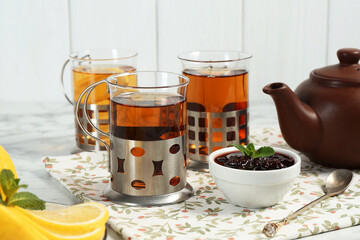 Glasses of tea in metal holders served on white table, closeup