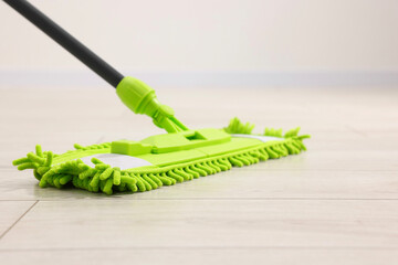 Microfiber mop on wooden floor indoors, closeup. Cleaning equipment