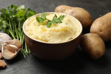 Delicious mashed potato with parsley and garlic on black table, closeup