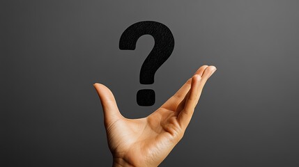 A single hand holds a black question mark on plain white, a symbol of doubt, inquiry, and answers.