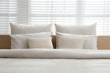 Comfortable bed with soft linens in stylish room, closeup. Interior design