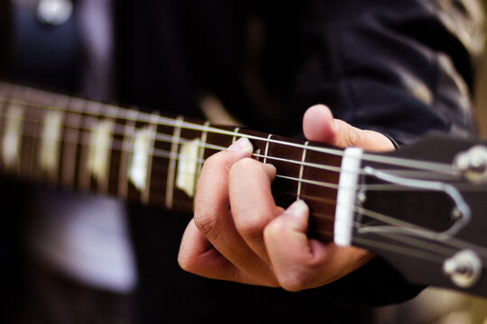 Young person fingering strings on guitar