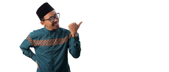 Asian Muslim man pointing at empty copy space with a thumbs-up gesture, expressing approval and positivity, isolated on a white background