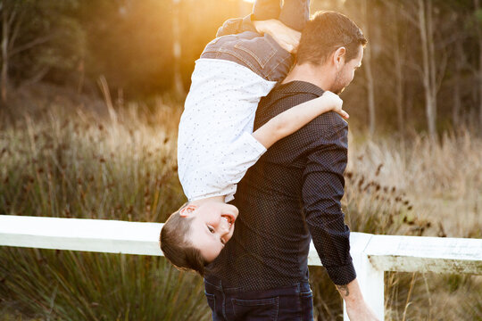 Father tipping son over his shoulder to carry him