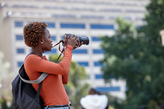 Young female photographer taking a picture in the city with dslr