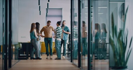 Business team in a modern open space startup office walking together. Diverse group of businesspeople smiling while having a discussion. Successful mixed race colleagues collaborating on a new project - Powered by Adobe