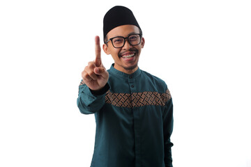 Naklejka premium Excited Asian Muslim man raising one finger 1 with a big smile, making a number one or first place gesture while looking at the camera, isolated on a white background