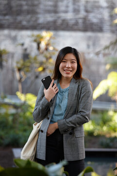 Young Asian woman with shopping bag outdoors at enclave