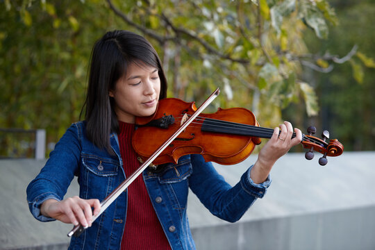 Young Asian female violin player practising outdoors