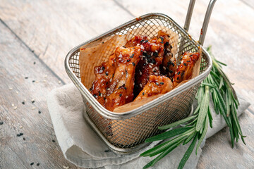 Iron basket with grilled chicken wings in barbecue sauce and sesame seeds