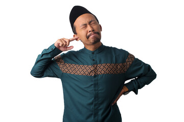 Asian Muslim man itching and putting a finger in his ear, trying to ignore unpleasant sounds during Ramadan fasting, isolated on a white background