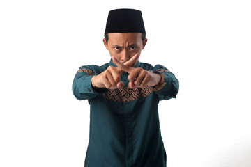 Asian Muslim man frowning with a serious expression, crossing his index fingers in an "X" gesture to signal prohibition, stopping forbidden actions during Ramadan fasting. Isolated on white background