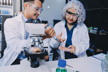 Team Asian scientists in a lab conducting food research using a microscope and lab equipment,...
