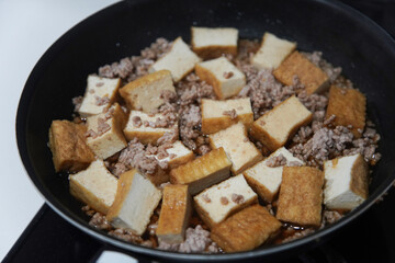 厚揚げとひき肉の煮物を作る様子