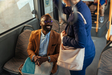 Stylishly dressed black man talking to a woman on the bus