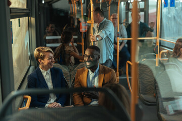Two colleagues sitting together as they commute to work by bus